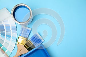 Flat lay composition with can of paint, brush and renovation tools on blue background