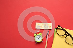 Flat lay composition of card with inscription HAPPY TEACHER`S DAY and stationery on red background