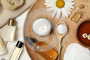 Flat lay composition with chamomile and cosmetic products on white wooden table