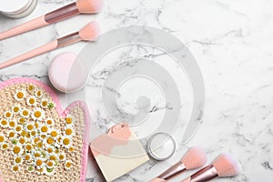 Flat lay composition with chamomile flowers and cosmetic products on marble table, space for text