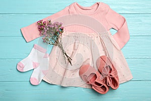 Flat lay composition with child`s clothes and flowers on blue wooden table