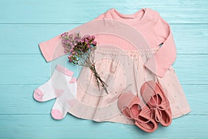 Flat lay composition with child`s clothes and flowers on blue wooden table