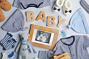 Flat lay composition with child`s clothes, ultrasound photo and word Baby on background