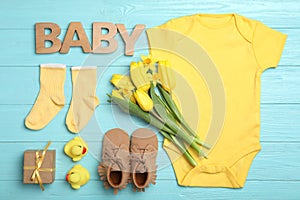 Flat lay composition with child`s clothes and word Baby on blue wooden table