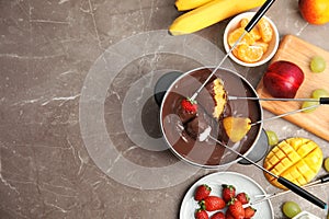 Flat lay composition with chocolate fondue in pot, fruits and space for text photo