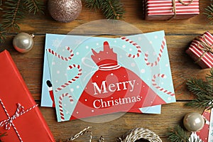 Flat lay composition with Christmas cards and festive decor on wooden background