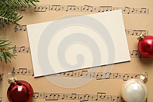 Flat lay composition with Christmas decorations and blank card on music sheets