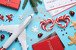 Flat lay composition with Christmas decorations, toy airplane and passports on light blue background. Winter vacation