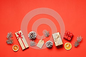 Flat lay composition of christmas gift box, tag, Dried orange fruits, fir branche, on a red background