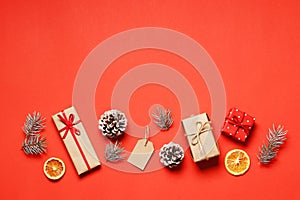 Flat lay composition of christmas gift box, tag, Dried orange fruits, fir branche, on a red background photo