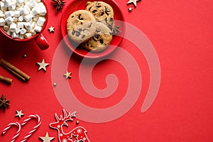 Flat lay composition with christmas pastry cookies, hot chocolate with marshmallows, cinnamon sticks, candy canes on red