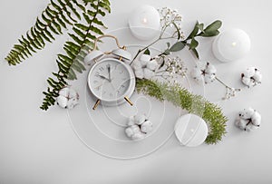 Flat lay composition with clock, burning candles, cotton flowers and tropical leaves on white background