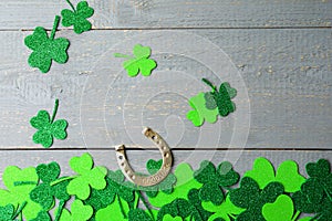 Flat lay composition with clover leaves and horseshoe on grey wooden background. St. Patrick`s day