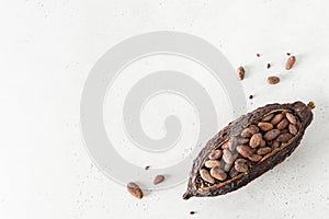 Flat lay composition with cocoa beans and cocoa pods on white concrete background. Organic food, natural chocolate. Top view, copy