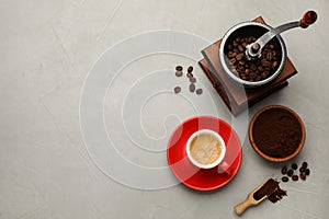 Flat lay composition with coffee grounds and roasted beans on light table, space for text