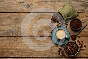 Flat lay composition with coffee grounds and roasted beans on wooden table, space for text