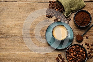 Flat lay composition with coffee grounds and roasted beans on wooden table, space for text