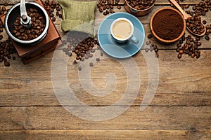 Flat lay composition with coffee grounds and roasted beans on wooden table, space for text