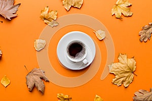 Flat lay composition with colorful Autumn cup of coffee and leaves on a color background. top view