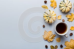 Flat lay composition with colorful Autumn cup of coffee and leaves on a color background. top view