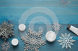 Flat lay composition with cosmetic products and snowflakes on turquoise wooden table, space for text. Winter skin care