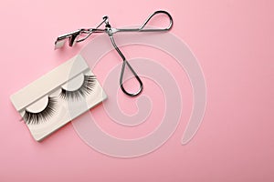 Flat lay composition of curler and false eyelashes on color background