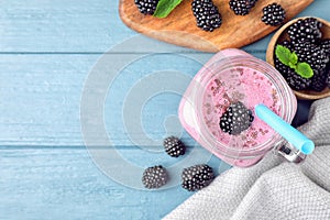 Flat lay composition with delicious blackberry smoothie on blue wooden background