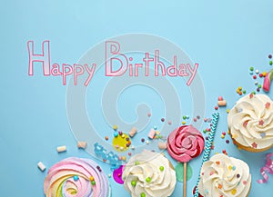 Flat lay composition with delicious cupcakes and text Happy Birthday on blue background