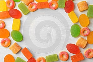 Flat lay composition with delicious jelly candies on wooden background