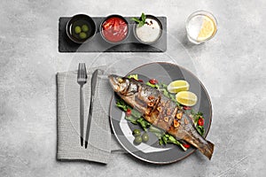 Flat lay composition with delicious sea bass fish, sauces and ingredients served on light grey table