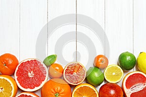 Flat lay composition with different citrus fruits on white wooden background