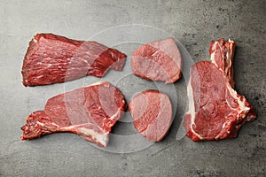 Flat lay composition with different fresh beef cuts on grey table