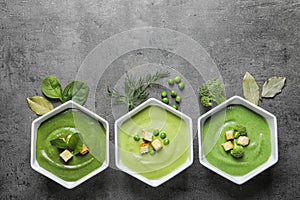 Flat lay composition with different fresh vegetable detox soups made of green peas, broccoli and spinach in dishes on table.