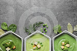 Flat lay composition with different fresh vegetable detox soups made of green peas, broccoli and spinach in dishes on table.