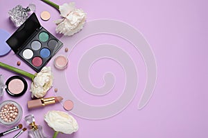 Flat lay composition with different makeup products and beautiful flowers on violet background, space for text