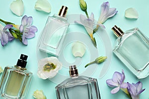 Flat lay composition of different perfume bottles and flowers on cyan background