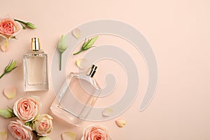 Flat lay composition with different perfume bottles and fresh flowers on beige background, space for text