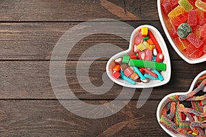 Flat lay composition with different yummy candies in heart shaped bowls and space for text