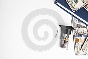 Flat lay composition with dollar banknotes and student graduation hat on white background. Tuition fees concept