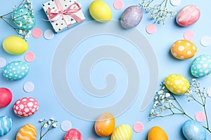 Flat lay composition with Easter eggs, present and flowers on color background, space for text