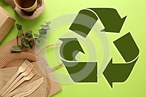 Flat lay composition with eco friendly products and recycling symbol on light green background