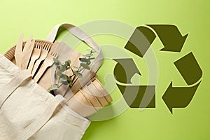 Flat lay composition with eco friendly products and recycling symbol on light green background