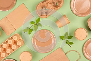 Flat lay composition with eco-friendly tableware and kraft paper food packaging on green background. Sustainable packaging,