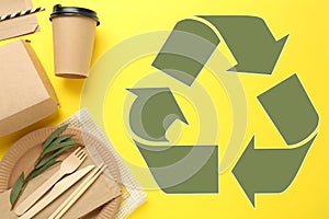 Flat lay composition with eco friendly tableware and recycling symbol on yellow background