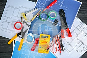 Flat lay composition with electrical tools and house plans on wooden background