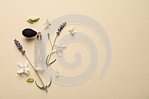 Flat lay composition with elegant perfume and flowers on beige background, space for text
