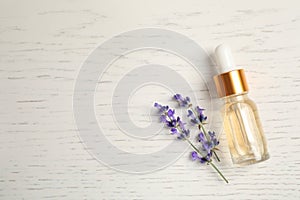 Flat lay composition with essential oil and lavender flowers on white wooden background. Space for text