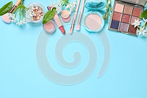 Flat lay composition with eyeshadow palette and beautiful flowers on light blue background, space for text