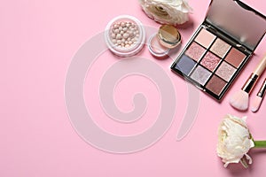 Flat lay composition with eyeshadow palette and beautiful flowers on pink background, space for text