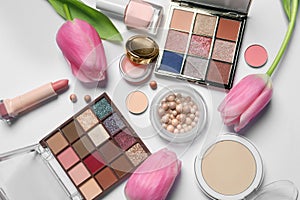 Flat lay composition with eyeshadow palettes and beautiful flowers on white background